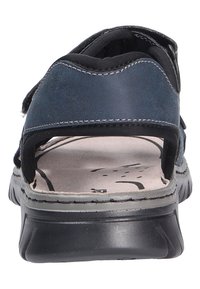 Dark blue sandal featuring a smooth leather upper, open heel, adjustable straps, and a cushioned insole with a textured surface.