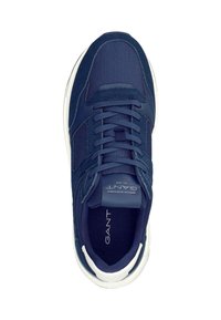 Námořnické modré tenisky s textilním a semišovým svrškem, bílou podrážkou, plochými tkaničkami a polstrovaným jazykem. Na jazyku a na boku mají logo.