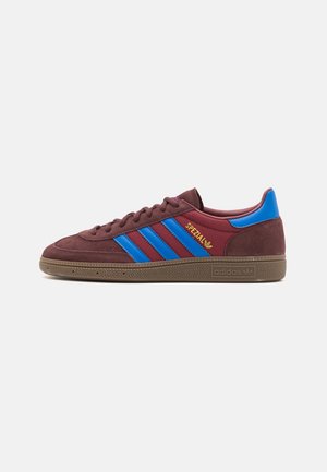 Low-top Adidas sneaker i mørkerød ruskind med blå striber, blå hælflap, gummisål og guld "Spezial" branding på siden.