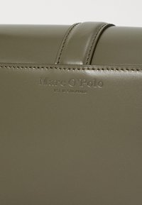 Olivovo zelená kožená taška s hladkým povrchom, so subtílnym prešívaním a embosovaným logom značky Marc O'Polo.