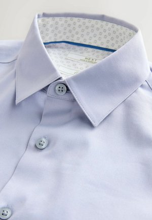 Hele sinine kaelusega särk kahe nupuga. Valmistatud siledast kangast, millel on mustriline sisemine krae vooder ja kontrastne õmblus.