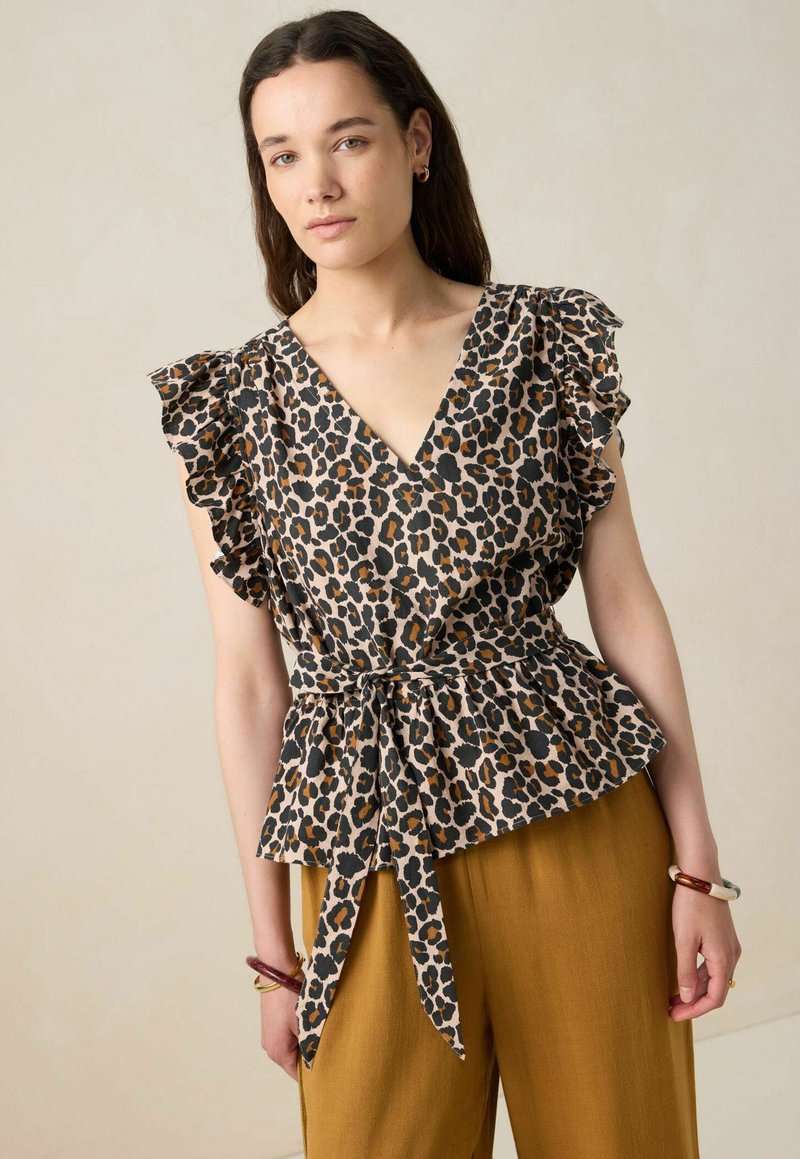 Blouse peplum à imprimé léopard avec un décolleté en V, des manches froncées et un détail noué à la taille. Le tissu présente des tons marron, noir et beige.