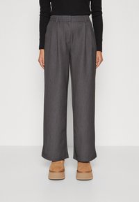 Grijze wijde broek van textuurstof met voorplooien, een hoge taille en een ontspannen pasvorm, gecombineerd met beige schoenen.