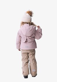 Ensemble d'extérieur pour enfants : veste rose clair avec capuche et ventilation dans le dos, et pantalon beige avec poignets élastiques. Bonnet en tricot blanc avec un pompon en fourrure.
