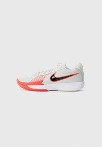 Nike sneakers featuring a white mesh upper with red accents, black Swoosh, and textured sole. Design is low-top with lacing system.