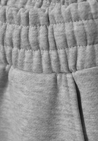 Γκρι φόρμες με υφασμάτινη ζώνη μέσης με υφή, που διαθέτει ριμπ μοτίβο και λείο ύφασμα. Η κοντινή λήψη τονίζει την απαλότητα του υλικού.
