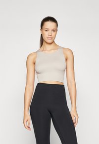 Beige kort tanktop med ribbet tekstur og brede stropper, kombinert med høyt midje svarte leggings. Enkel, stilren design.