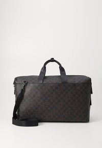 Brown checkered travel bag in textured material. Features black leather handles, a detachable shoulder strap, and a zip closure.