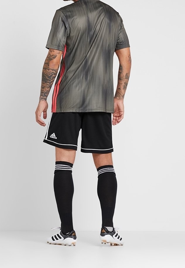 Harmaa ja musta raidallinen urheilu paita, jossa on punaisia yksityiskohtia, yhdistettynä mustiin shortseihin ja polvipituisii mustiin sukkiin, joissa on valkoiset raidat.