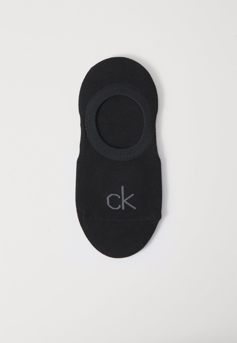 Μαύρη χαμηλή κάλτσα με σταθερό σχέδιο, κυκλικό άνοιγμα και ελαστική μανσέτα; διαθέτει ένα διακριτικό γκρι λογότυπο "ck" στο πλάι.