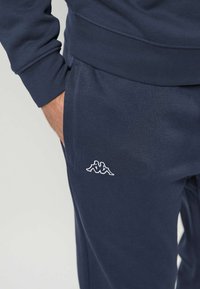 Marineblå bomullssweatpants med sidelomme og brodert Kappa-logo på låret. Myk tekstur med en avslappet passform.