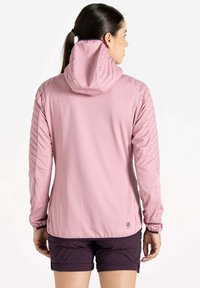 Helle rosa Jacke mit langen Ärmeln, featuring eine Kapuze, strukturierte Schulternähte und elastische Bündchen, getragen mit dunklen Shorts.