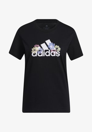 Persoon die een zwart Adidas T-shirt draagt met een kleurrijk bloemenlogo en lichtgrijze joggingbroek, getoond van nek tot heupen.