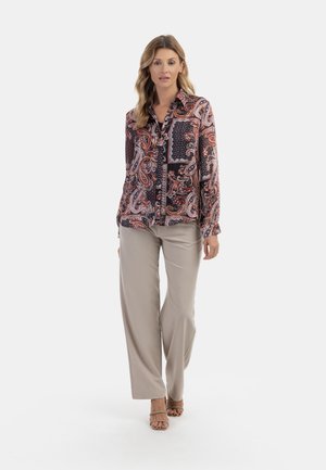 Camicia a maniche lunghe con bottoni, caratterizzata da una stampa paisley in tonalità scure con accenti arancioni e bianchi, abbinata a pantaloni a gamba larga beige chiaro.