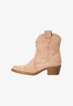 Bota occidental beige de ante hasta el tobillo con tacón bajo apilado, costuras decorativas y lengüeta para tirar, sobre fondo blanco.