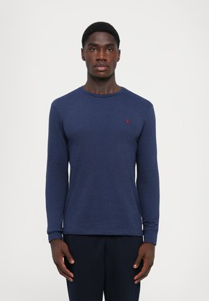 Navy lange mouwen shirt van gestructureerde stof, met een ronde hals en een klein rood logo op de linkerbovenborst. Strak ontwerp.