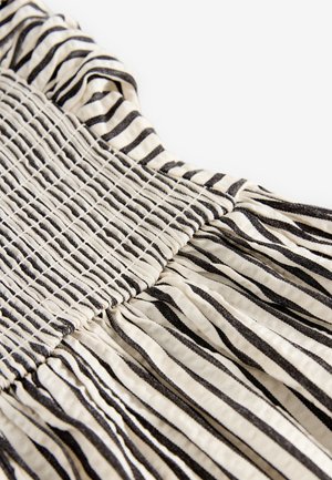 Stribet kjole med en smocket overdel med sorte og cremefarvede vandrette striber, tekstureret stof og subtil samling ved kanten.