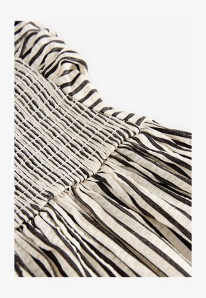 Stribet kjole med en smocket overdel med sorte og cremefarvede vandrette striber, tekstureret stof og subtil samling ved kanten.