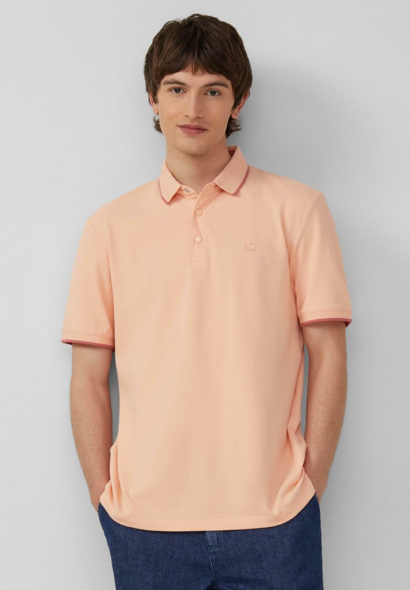 Pfirsichfarbendes Polo-Shirt mit zwei Knöpfen, geripptem Kragen und Bündchen, versehen mit burgunderfarbenen Akzenten, aus hochwertigem, glattem Baumwollgemisch.