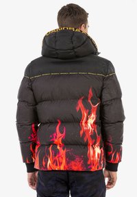 Schwarze Pufferjacke mit Kapuze, ausgestattet mit lebendigen orangefarbenen und roten Flammenmotiven am Saum sowie gelben Logoakzenten am Kragen.