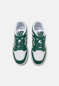 Scarpe da atletica verdi e bianche con tomaia in pelle e mesh, caratterizzate da perforazioni, lacci rotondi e un logo sulla linguetta.