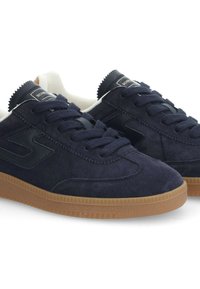 Baskets en suède marine avec des accents en cuir noir, doublure blanche et semelle en caoutchouc gum. Elles présentent des lacets plats et un design de couture texturé.