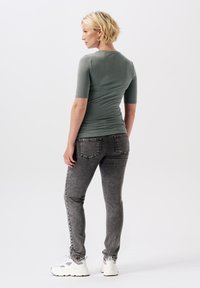 Grå kortärmad topp, figursydd design, kombinerad med grå jeans med bakfickor. Vita sneakers med mönstrade detaljer fulländar looken.