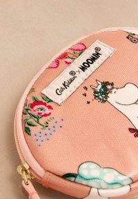 Okrogla rožnato z fabricanjasta torbica z cvetličnimi vzorci in likom Moomin, z zlatim zadrgo in belim etiketom, na katerem so napisane blagovne znamke.