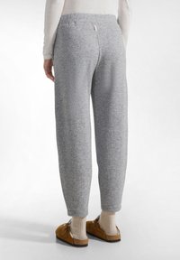 Pantaloni de trening gri, dintr-un material catifelat, cu un croi lejer. Prezintă un elastic la talie și un design cu picioare conice, oferind confort și libertate de mișcare.