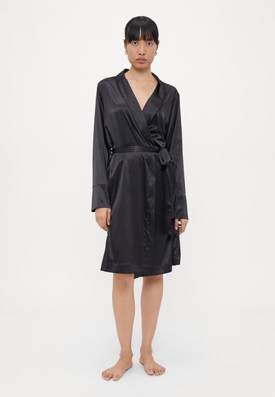Robe en satin noir avec des manches longues, design enveloppant et ceinture à la taille. Texture lisse et coupe mi-longue. Fini brillant qui rehausse l'élégance du tissu.