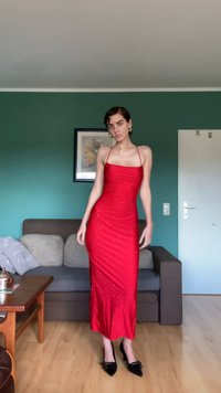 Röd satindress med en figurnära silhuett, fyrkantig halsringning och tunna axelband, prydd med små detaljer. Bärs med svarta klackar.