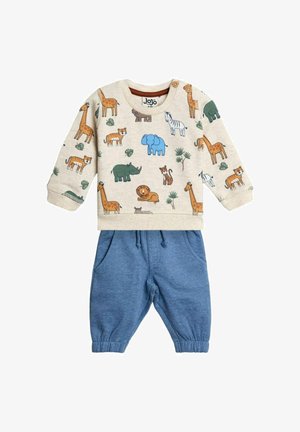 Béžová mikina z bavlny s potiskem zvířat, doplněná modrými tepláky se šňůrkou. Má dlouhé rukávy a elastické manžety.