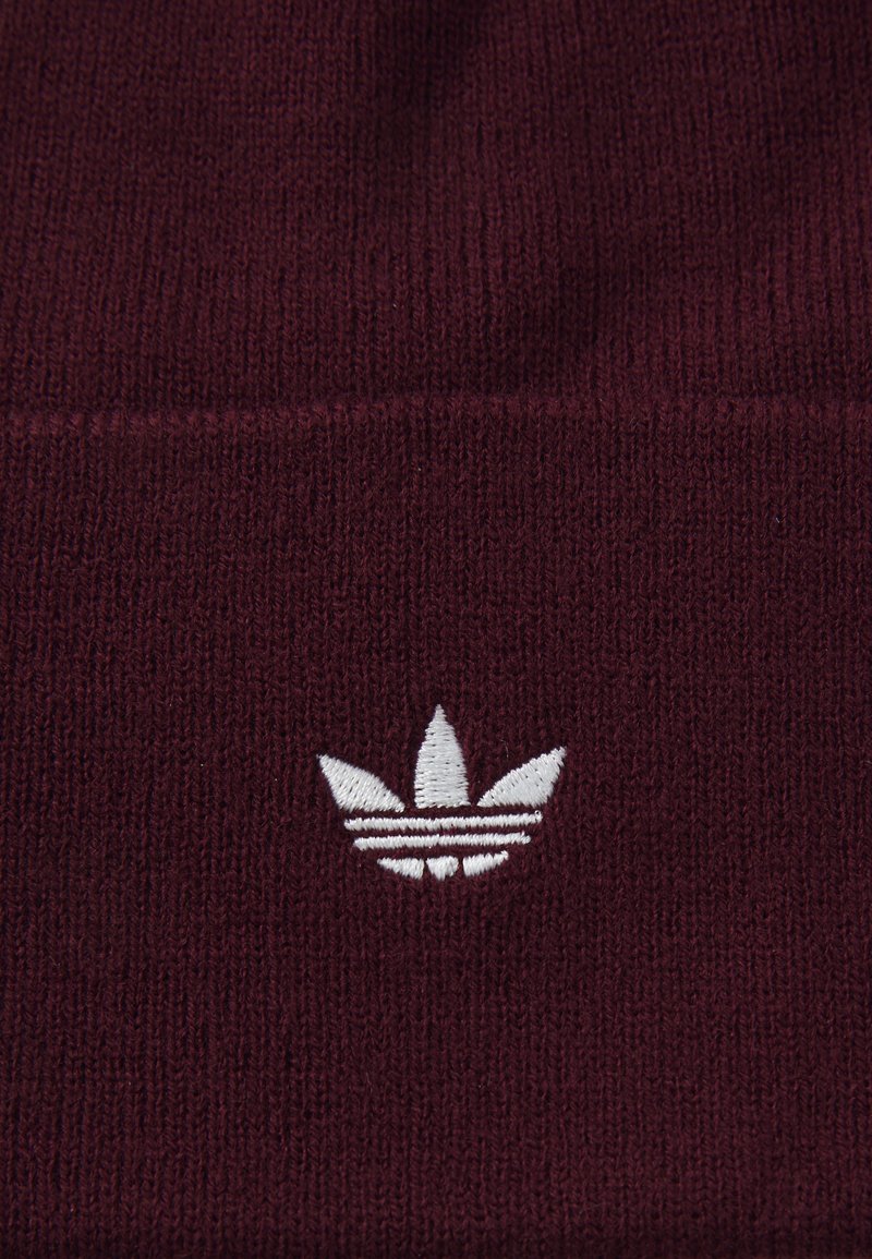 Bordeaux gebreide beanie met een witte geborduurde drie-strepenlogo aan de voorkant. Zachte textuur met een aansluitend ontwerp.