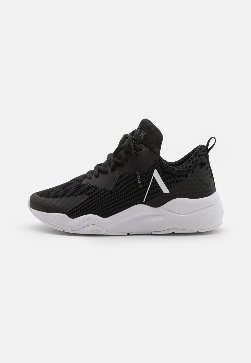 Baskets de sport noires avec semelle blanche, dessus en mesh, fermeture à lacets, languette au talon et logo angulaire blanc sur le côté.
