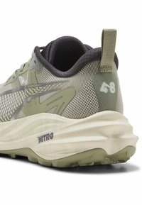 Zapatilla verde claro con parte superior de malla, forro negro suave, detalles texturizados y una suela prominente en blanco y gris con la marca "NITRO".