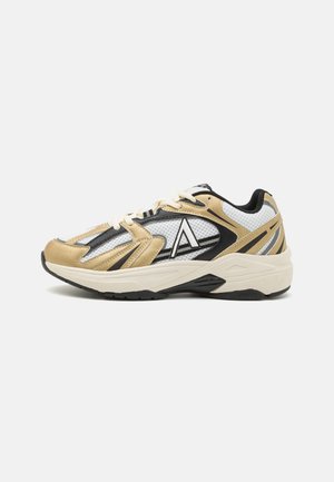 Sport shoes with a mesh upper in gold, black, and white. Features a thick white midsole, textured black outsole, and logo accents.