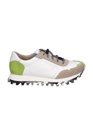 Sneaker aus weißem und beigem Leder, mit grünen Wildlederakzenten, schwarzen Schnürsenkeln und einer strukturierten Sohle mit auffälligen Profilen für besseren Halt.