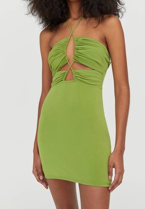 Robe mini verte avec découpes froncées sur la poitrine et le ventre, dotée de fines bretelles croisées sur les épaules et la poitrine.