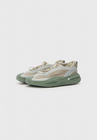 Sneakers with a mesh and synthetic upper in light gray and green hues, featuring a textured sole and elastic laces for a secure fit.
