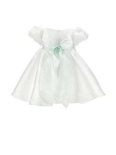 Weißes Babykleid aus Satin mit Puffärmeln und einer großen durchsichtigen mintgrünen Schleife, die in der Taille gebunden ist, vor einfachem Hintergrund.