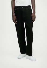 Melna denima bikses ar taisnu griezumu, piecām kabatām un sudraba detaļām. Apvienotas ar baltām kedām un vienkāršu baltu krekli.