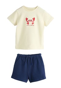 Chemise crème à manches courtes avec un dessin de crabe rouge et le texte « gone crabbing », associée à un short bleu marine avec ceinture élastique.