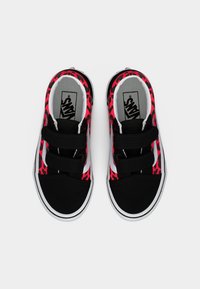 Ζευγάρι μαύρων και κόκκινων sneakers Vans με λεοπάρ σχέδιο, λευκές σόλες και δύο μαύρα αυτοκόλλητα λουράκια, σε άποψη από πάνω σε λευκό φόντο.