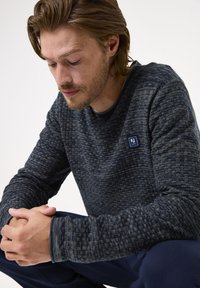 Marineblauer strukturierter Sweatshirt mit einem gewebten Muster, Rundhalsausschnitt und kleinem Logopatch auf der Brust. Lange Ärmel und gerippte Bündchen.