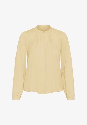 Long-sleeve beige blouse with a round collar, pleated details near shoulders, and buttoned cuffs on a plain background.
