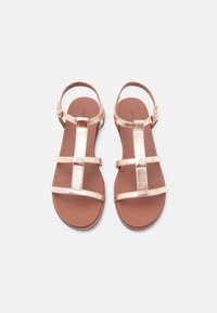 Ζευγάρι φλατ σανδάλια σε ροζ χρυσό με λουριά στον αστράγαλο και δαχτυλήθρες, απεικονισμένα σε λευκό φόντο, από πάνω.