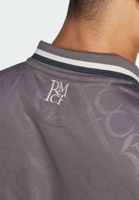 Polo grigio con un motivo sottile, colletto a righe a contrasto e logo ricamato "RM" sulla parte posteriore del collo.