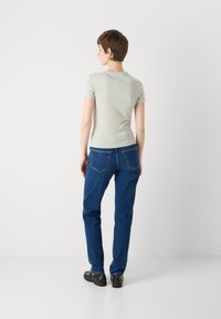Ljusgrön kortärmad t-shirt med rund halsringning, i kombination med mörkblå raka jeans med bakfickor och en lätt blekning.