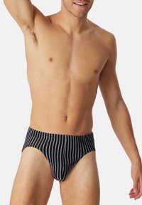 Caleçons pour hommes rayés noir et blanc avec une coupe ajustée et une ceinture élastique. Le tissu semble lisse avec un léger éclat.