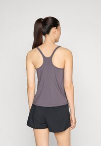 Grå, ærmeløs atletisk top med racerback-design og let, glat tekstur, parret med sorte atletiske shorts.